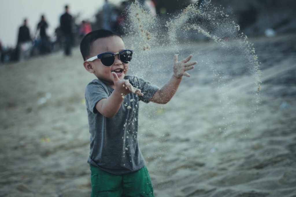 Boy with sunglasses playing on the beach