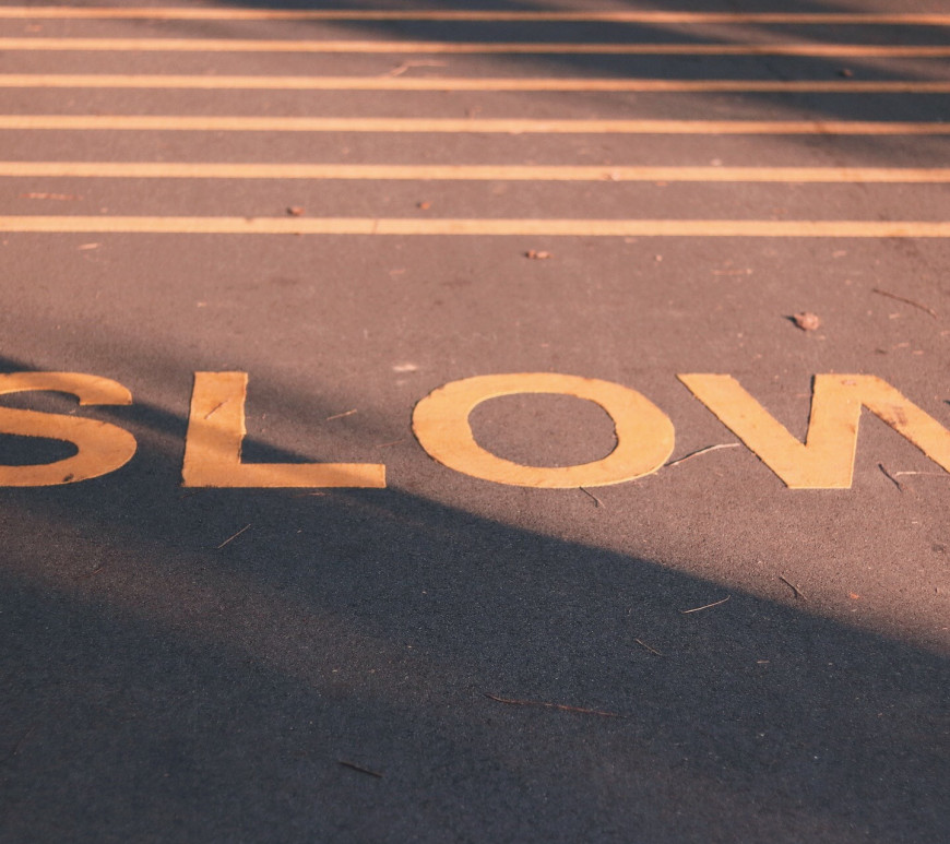 slow living: how do we slow down our lives to live more intentionally. Image of the word slow painted on the road.