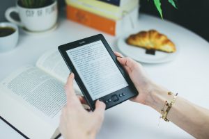 slow living: person holding kindle e book reader next to a real book